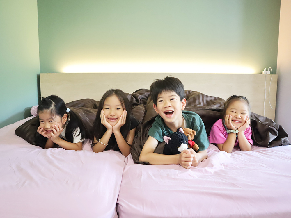 ホテル客室のベッドでくつろぐ子供達の写真